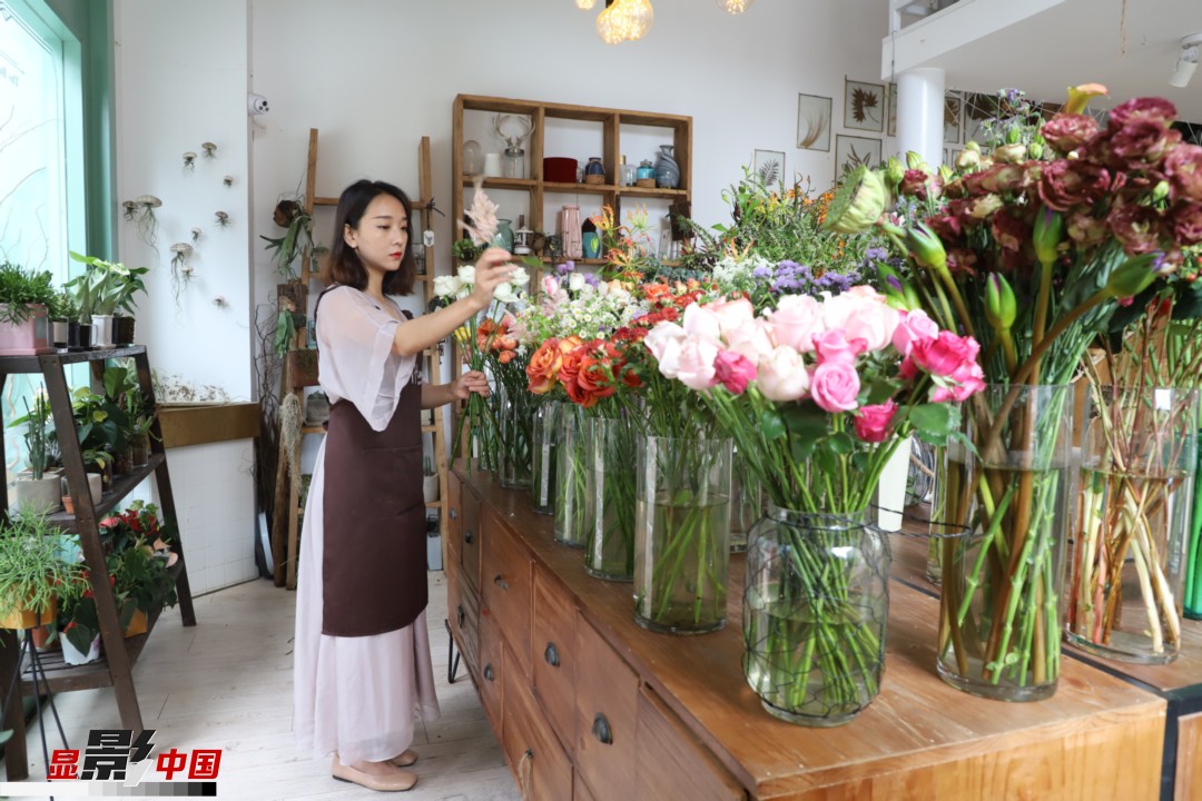 王黎媛是一名河南姑娘，在昆明念完大學(xué)后，就再也舍不下春城的藍(lán)天陽光、青山碧水，更舍不下這里的四時(shí)繁花，于是就干脆留了下來，成了一名媒體人。2017年的時(shí)候又毅然辭去工作，創(chuàng)業(yè)開起了花店，成了都市里的一名“花房姑娘”。圖為王黎媛在自己的花店中整理鮮花。新華網(wǎng) 周亞平/攝 念新洪/文
